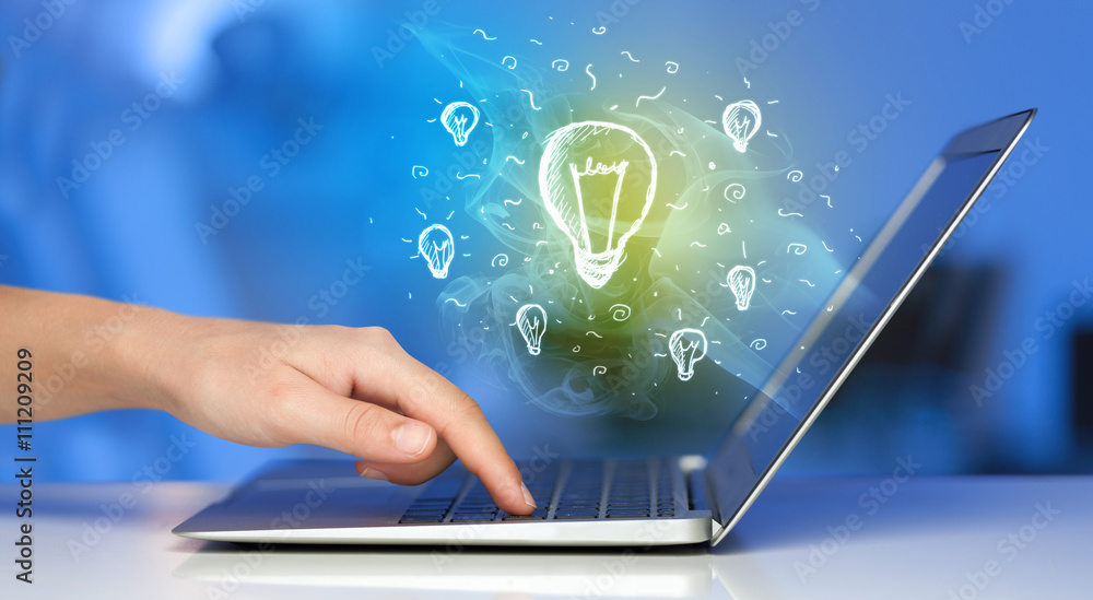 Close up of hand with laptop and idea bulb Close up of hand with laptop and idea bulb