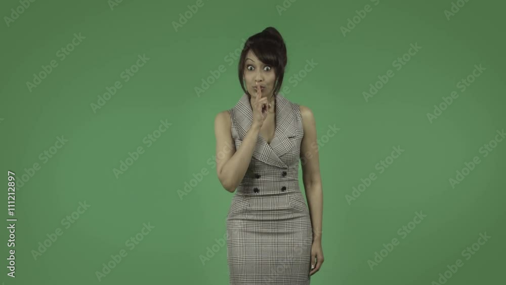 indian business woman isolated on green with fingers on lips indian business woman isolated on green with fingers on lips
