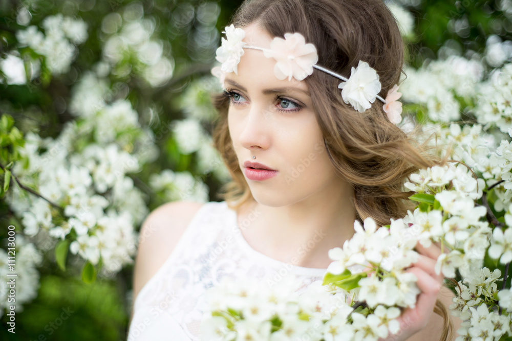 Fototapeta premium Spring / pretty woman with flower hair band in front of a blossoming apple tree
