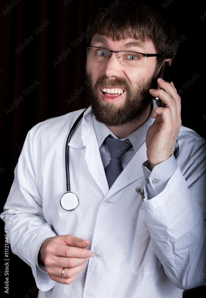 Dr. bearded manin a white medical robe, stethoscope on his neck, emotionally talking on phone Dr. bearded manin a white medical robe, stethoscope on his neck, emotionally talking on phone