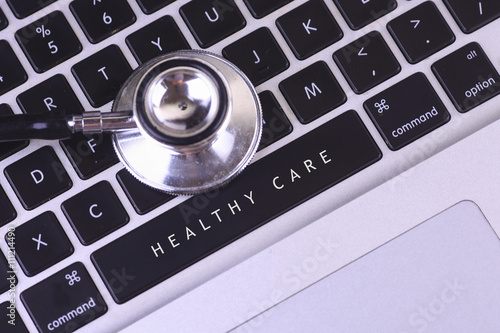 close up of stethoscope and HEALTHY CARE written on laptop keyboard