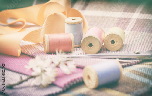 sewing supplies, needles, scissors on the colorful gunny textile background. Vintage filtered photo