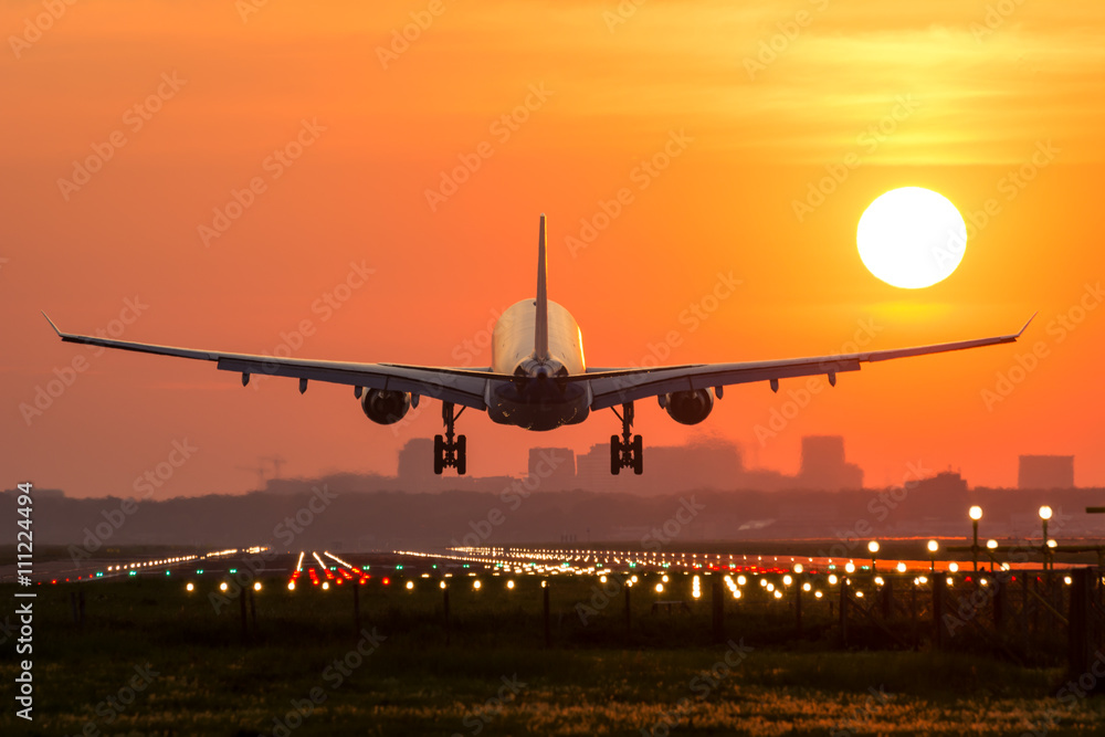 Naklejka premium Samolot pasażerski ląduje podczas cudownego wschodu słońca.