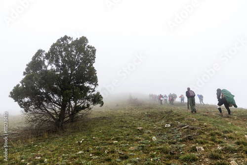 Group of tourists on the ascent through the mist. Mountains in Crimea, Russia Ukraine