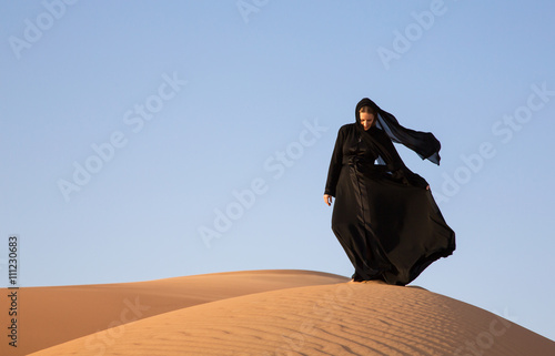 A woman in abaya in sanddunes in Liwa Desert, Aby Dhabi, UAE photo