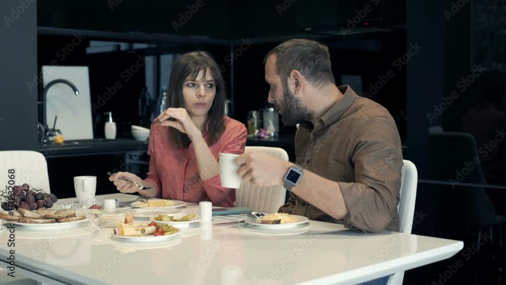 Young couple talking during breakfast in kitchen at home
Young couple talking during breakfast in kitchen at home