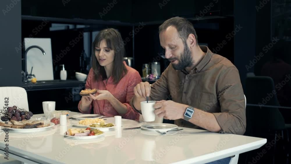 Young couple talking during breakfast in kitchen at home
Young couple talking during breakfast in kitchen at home