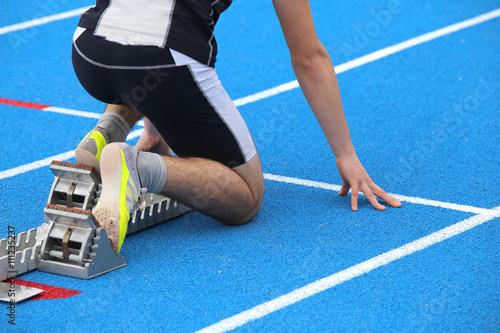 muscular athlete in the starting blocks of a athletic track photo