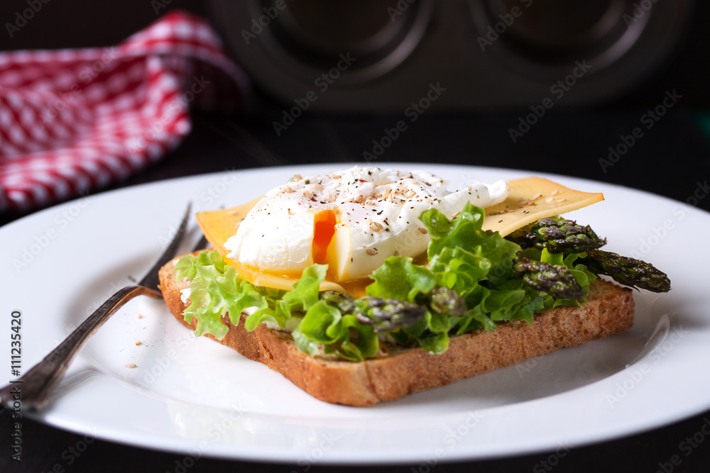 Toasted sandwich with salad leaves, asparagus, cheese and poached egg, closeup