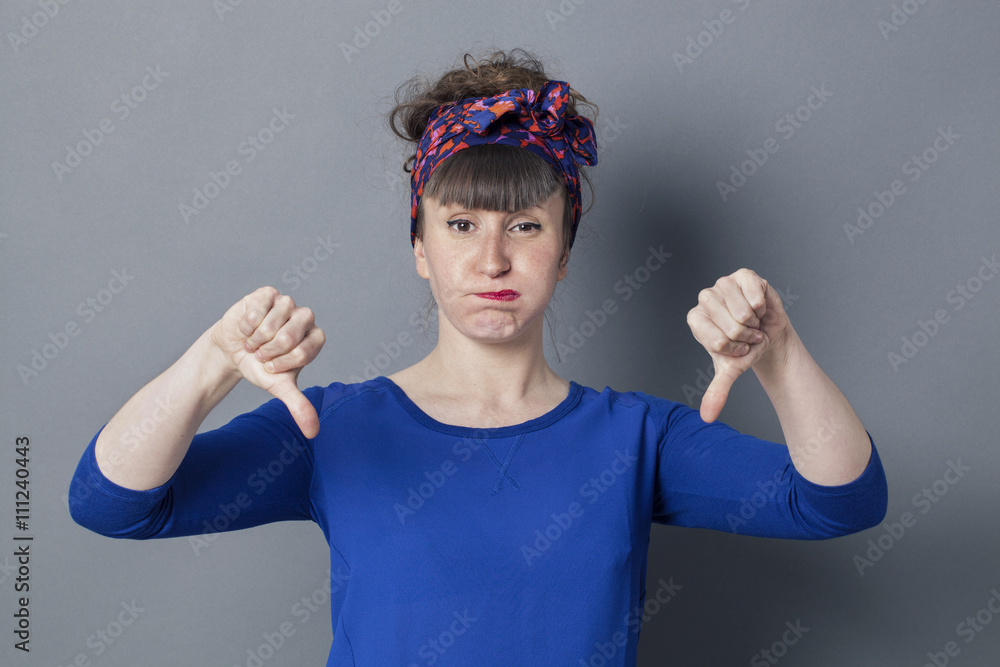 bored young woman with thumbs down blowing out her cheeks bored young woman with thumbs down blowing out her cheeks