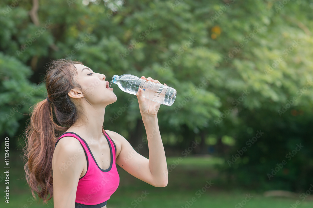 young attractive woman drinking water from plastic bottle in the park young attractive woman drinking water from plastic bottle in the park
