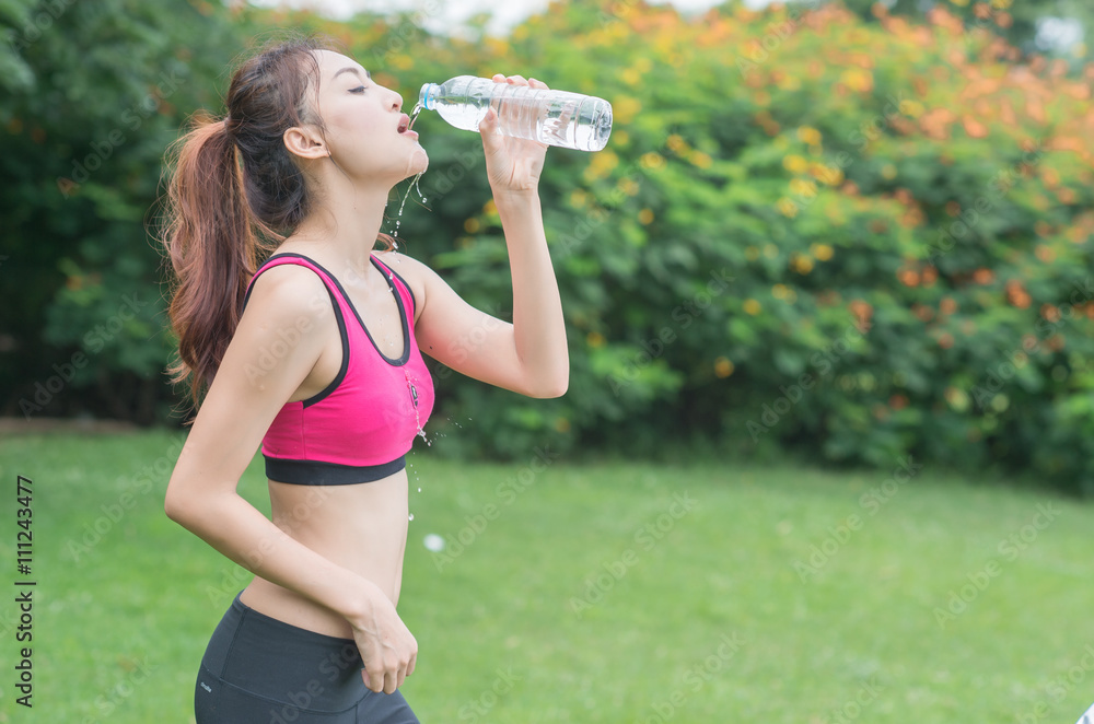 young attractive woman drinking water from plastic bottle in the park young attractive woman drinking water from plastic bottle in the park