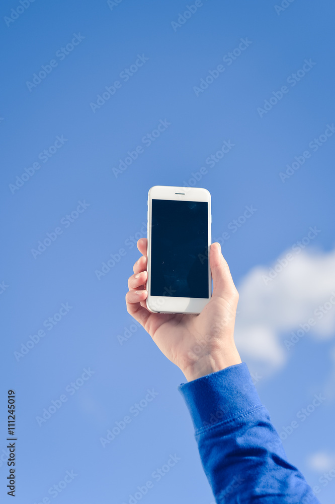 Holding mobile cell phone over blue sky white clouds background. Holding mobile cell phone over blue sky white clouds background.