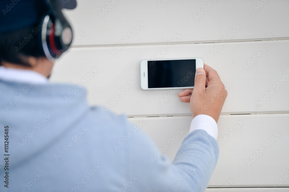 Man with headphones holding mobile smart phone on wooden outdoors background Man with headphones holding mobile smart phone on wooden outdoors background