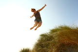 joy/ woman jumping for joy off a dune at the beach