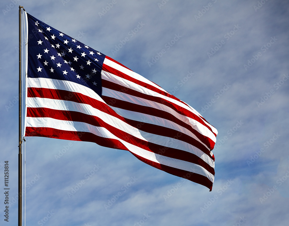 Fototapeta premium Flag USA in wind on blue sky and clouds
