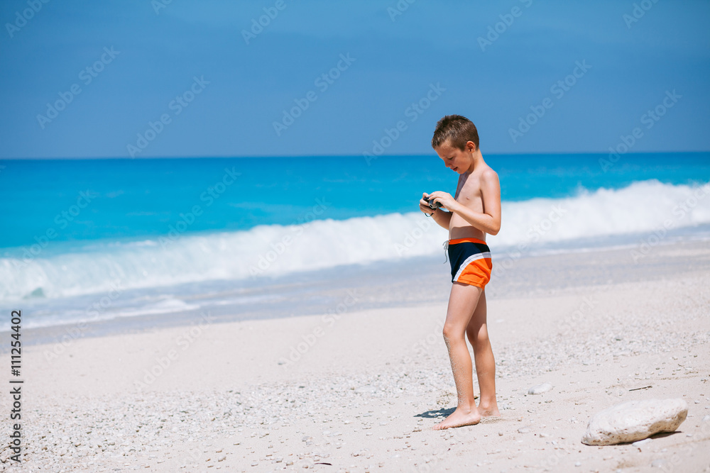 Beach vacation dream. Handsome young boy enjoying in beautiful tropical beach and taking some photos with his camera. Beach vacation dream. Handsome young boy enjoying in beautiful tropical beach and taking some photos with his camera.