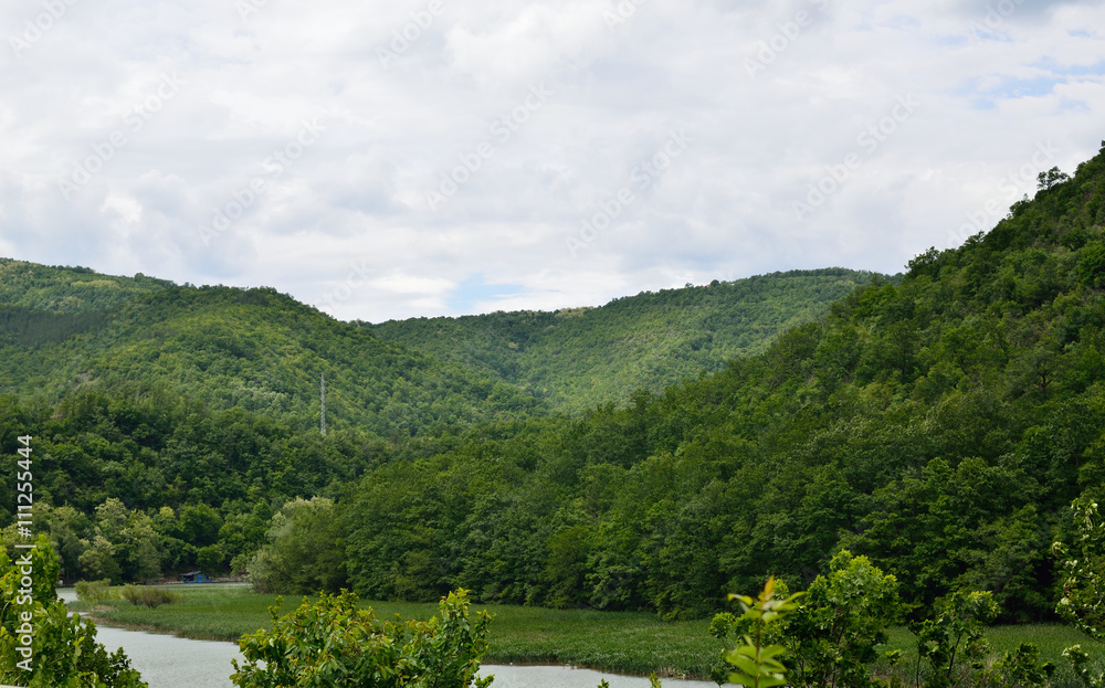 Hills,valleys and part of river under cloudy sky in spring Hills,valleys and part of river under cloudy sky in spring