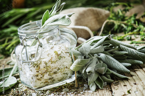 Sea salt, milled with sage in a glass jar, fresh herbs, vintage photo