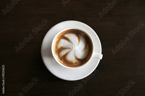 Cup of cappuccino art coffee with froth shape plumeria and woode