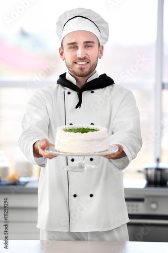 Male chef holding cake.