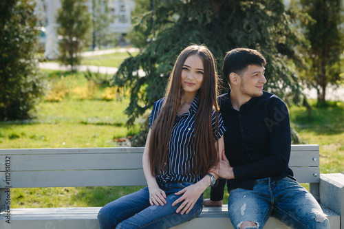 Loving young calm beautiful couple sitting on the bench 