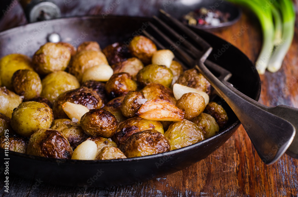Roasted young potatoes in a pan with garlic. Selective focus. Toned image Roasted young potatoes in a pan with garlic. Selective focus. Toned image
