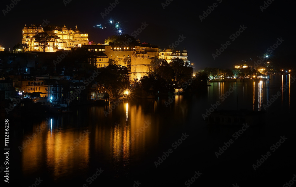 Horizontal panorama of the Udaipur City Palace and Pichola lake on the night with accent lighting, Rajasthan, India