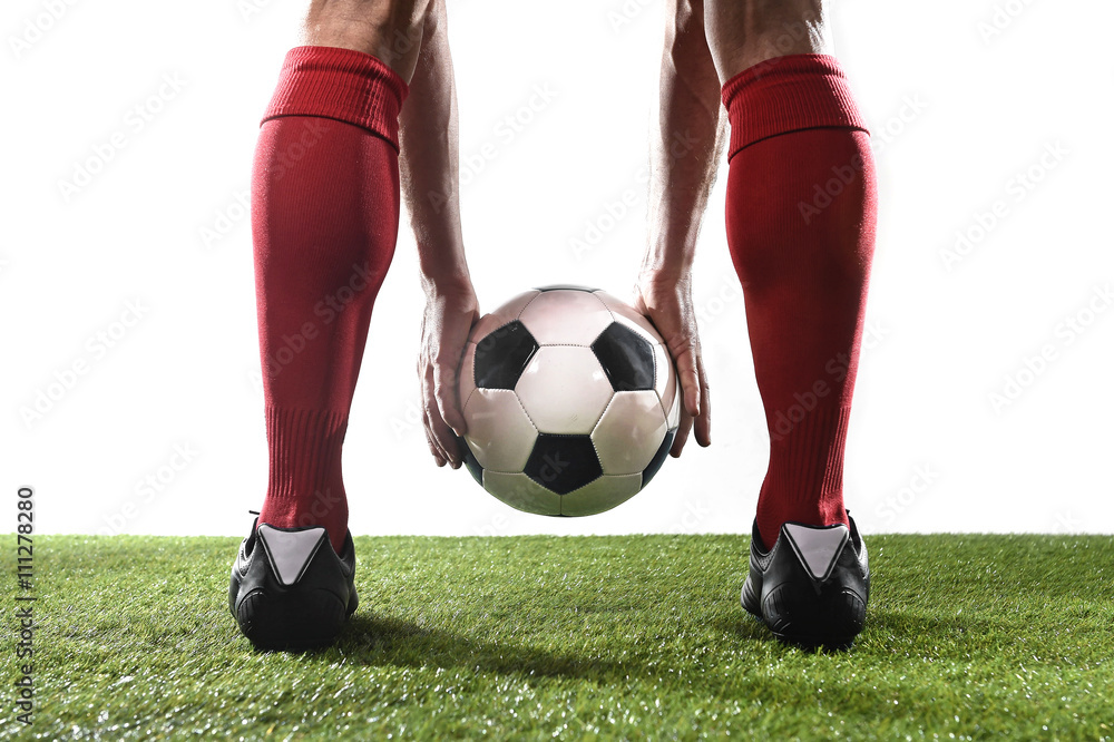Fototapeta premium legs of football player in red socks and black shoes holding the ball in his hands placing free kick