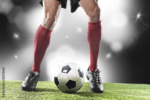  football player in red socks and black shoes running and dribbling with the ball playing on stadium © Wordley Calvo Stock