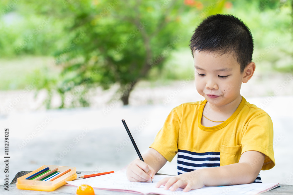 Little asian boy use pencil writing on notebook