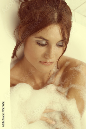 Young beautiful brunette woman takes bubble bath. Concept of care of body
