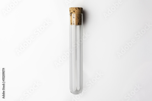 Empty glass transparent test tube closed with cork on white background