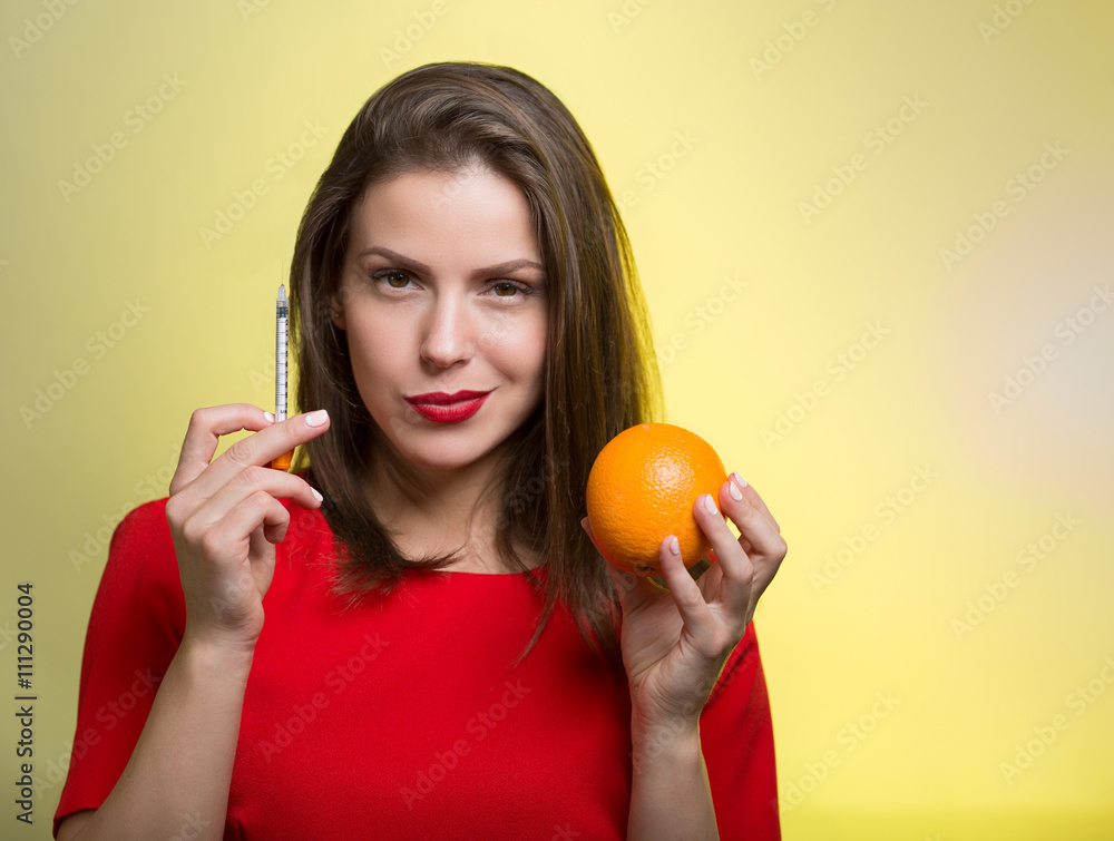 Woman holding a syringe and an orange Woman holding a syringe and an orange