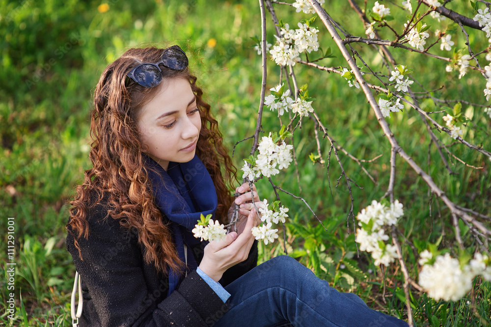 Fototapeta premium young woman in black coat walking in a blossoming spring garden