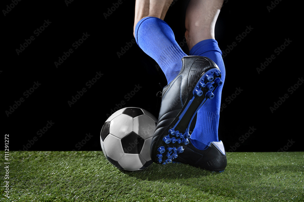 Fototapeta premium legs and feet of football player in action running and dribbling with the ball playing on green grass