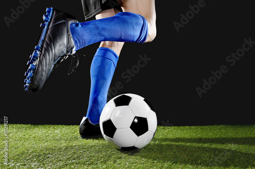  legs and feet of football player in action running and dribbling with the ball playing on green grass