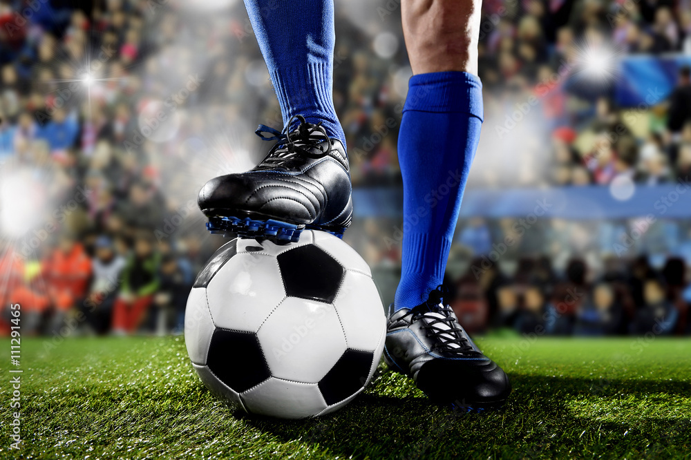 legs and feet of football player in blue socks and black shoes