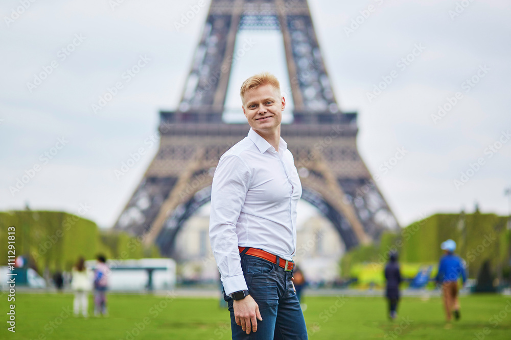 Handsome man in front of the Eiffel tower in Paris, France
