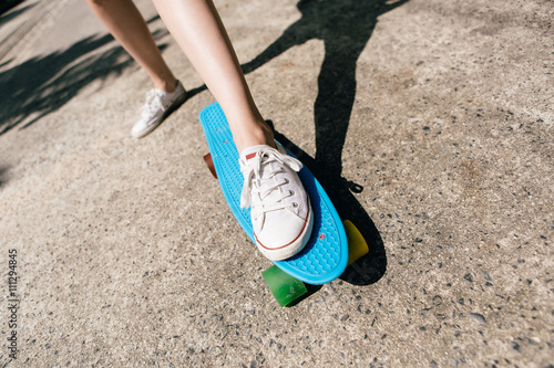 Young girl in sneakers on skateboard.