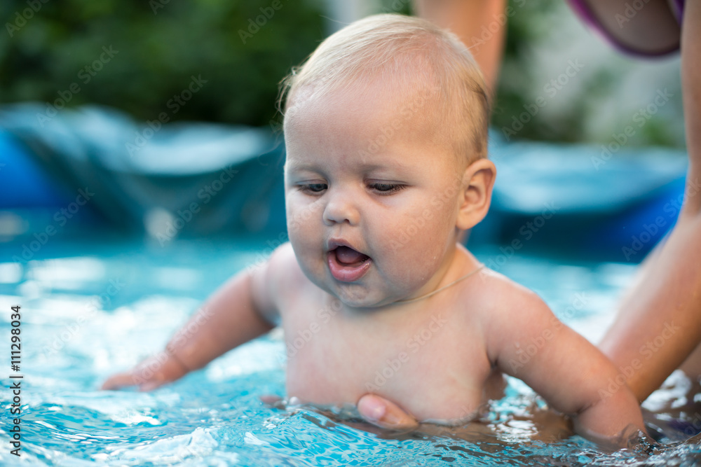 A cute happy young female girl child baby relaxing on the side of a swimming pool A cute happy young female girl child baby relaxing on the side of a swimming pool