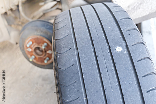 close up of screw nail puncturing car tire