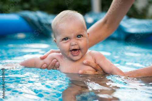 A cute happy young female girl child baby relaxing on the side of a swimming pool © lexmomot