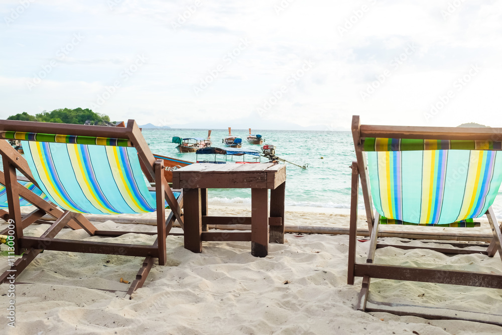Sun umbrellas and wooden beds on tropical beach.