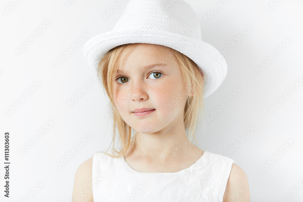 Lifestyle and people concept. Isolated headshot of beautiful Caucasian 5-year old female model with fair hair wearing stylish white clothes, looking and smiling at the camera with happy expression Lifestyle and people concept. Isolated headshot of beautiful Caucasian 5-year old female model with fair hair wearing stylish white clothes, looking and smiling at the camera with happy expression