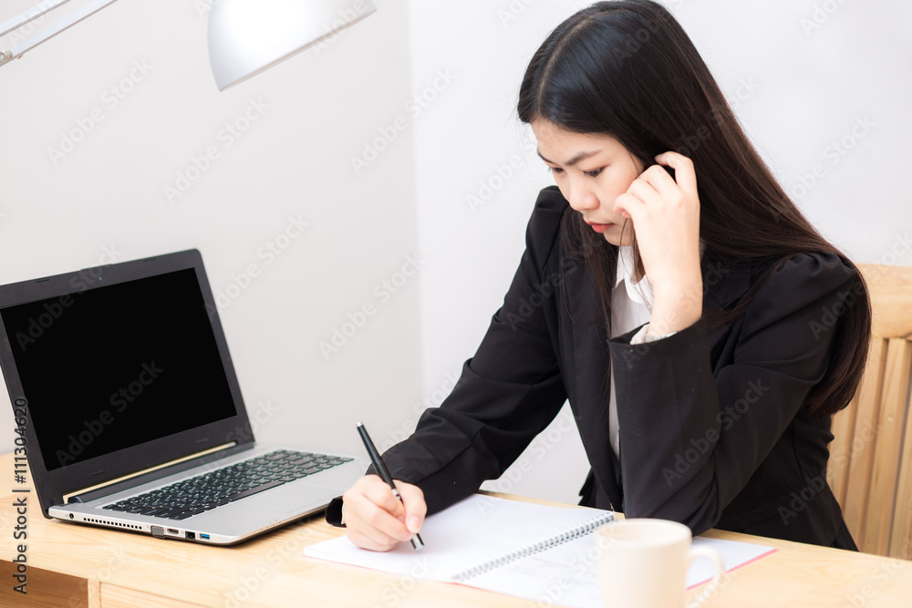 Portrait of business asian woman with laptop writes on a documen Portrait of business asian woman with laptop writes on a documen