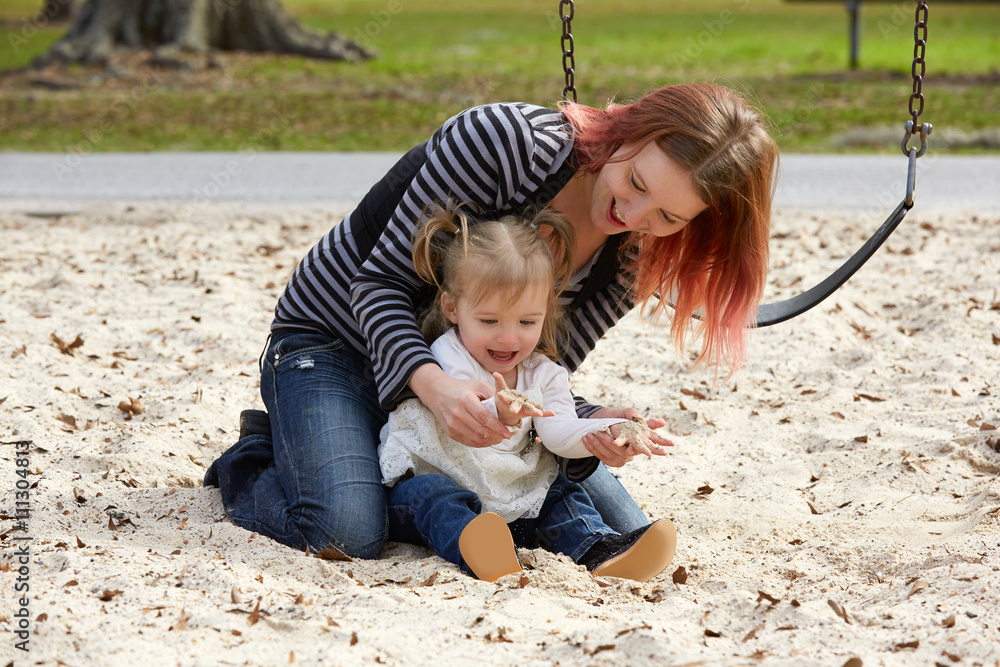 Mother and daughter playing with sand in park Mother and daughter playing with sand in park