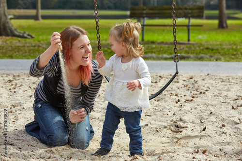 Mother and daughter playing with sand in park photo