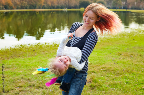 Mother and daughter playing with feathers in park photo