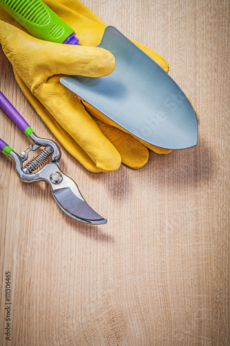 Protective gloves hand shovel secateurs on wooden board gardenin